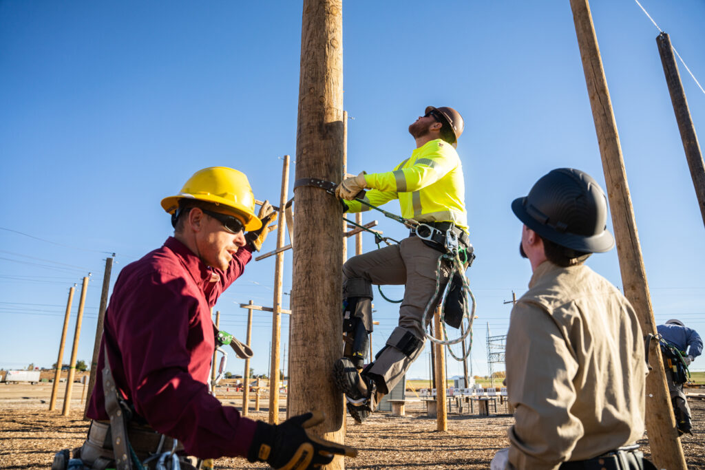 NLC Instructor pointing and teaching to a lineman climbing up a pole