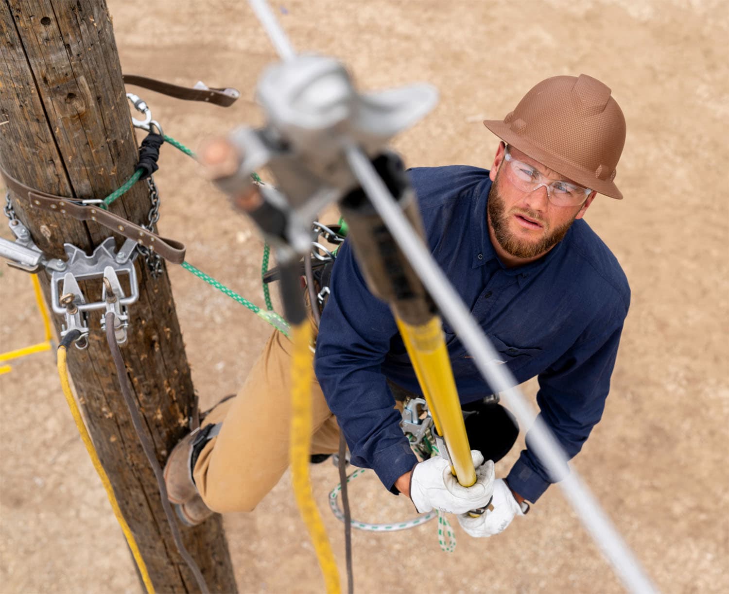 Lineman using hotstick on pole.