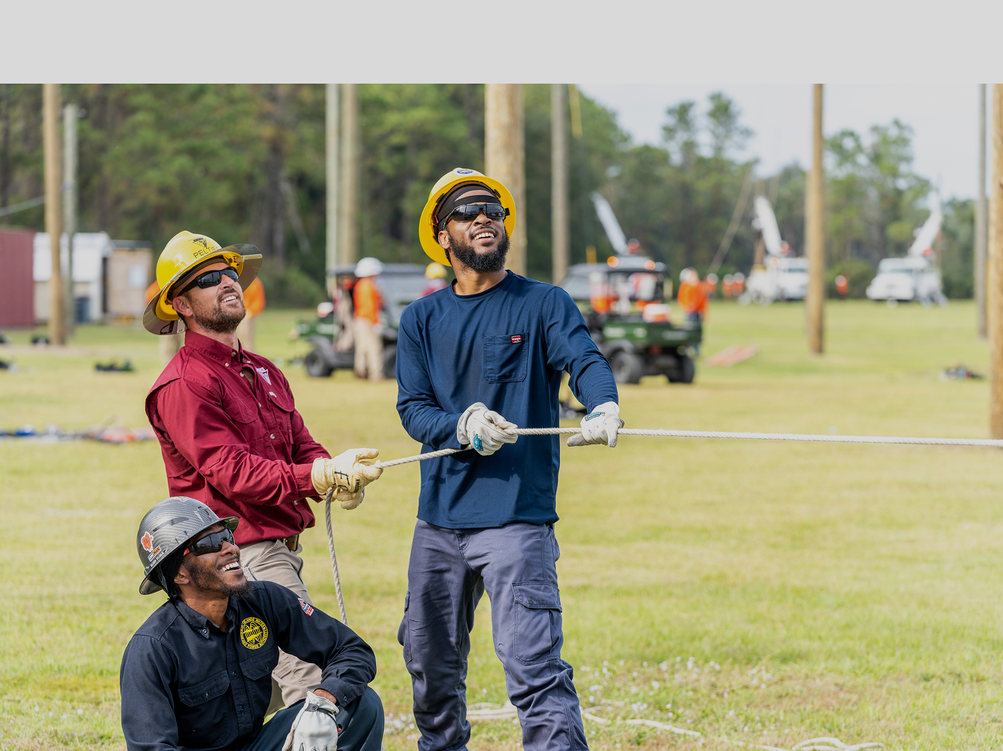 Three smiling linemen holding a lead as it sets | Northwest Lineman College