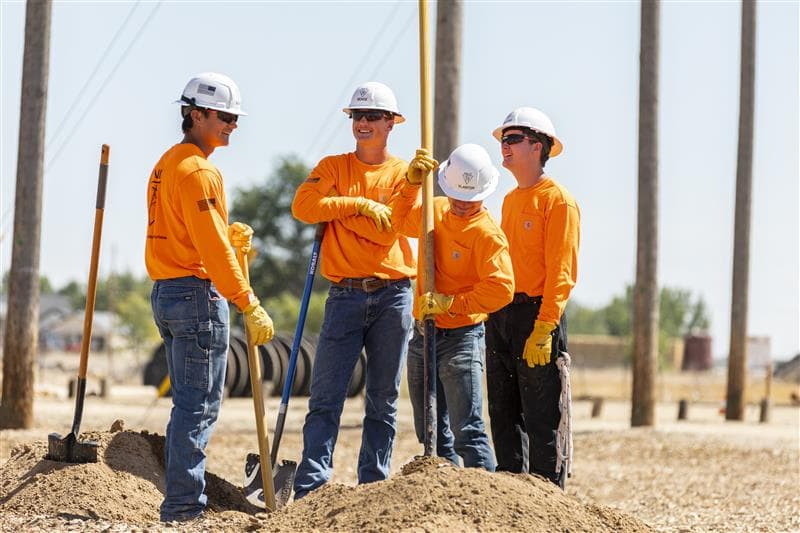 A group of lineman chatting while they work | Northwest Lineman College
