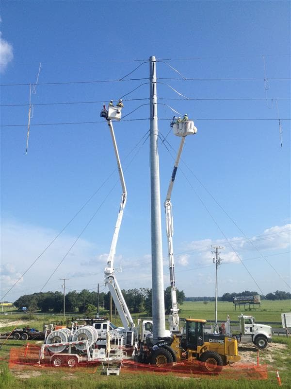 Lineworker team working on an electrical line next to a highway | Northwest Lineman College